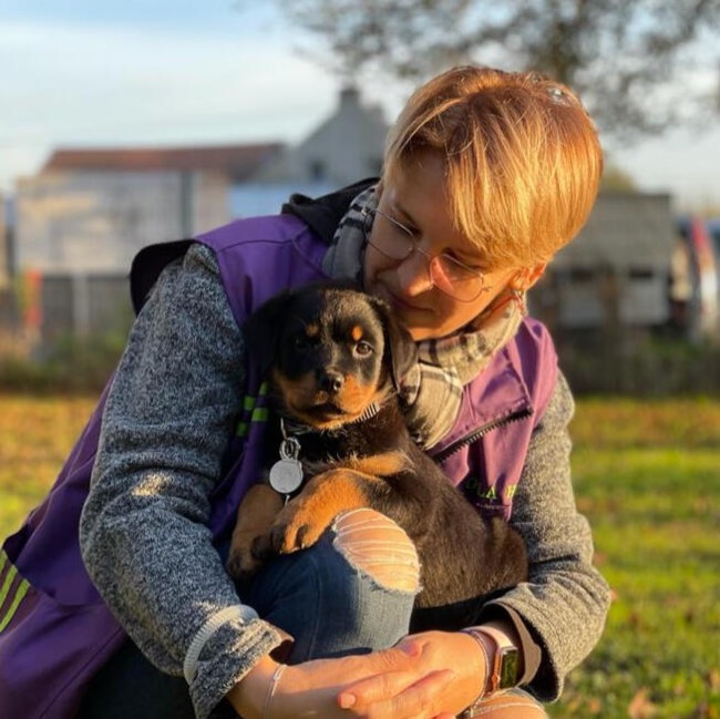 Une éducatrice serre un chiot Rottweiler dans ses bras
